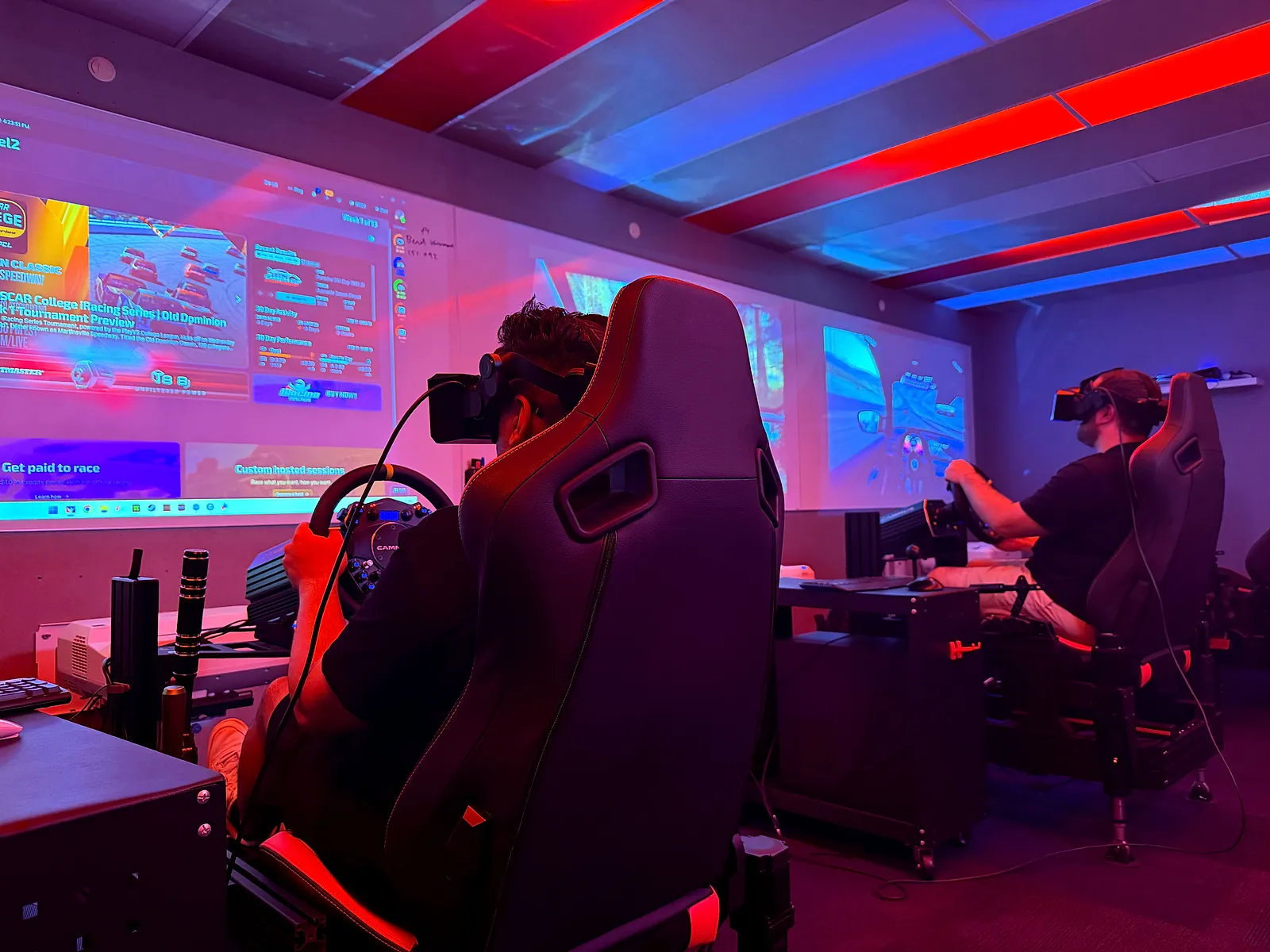 Full motion racing rigs facing projector screens at Sim Racing Adelaide